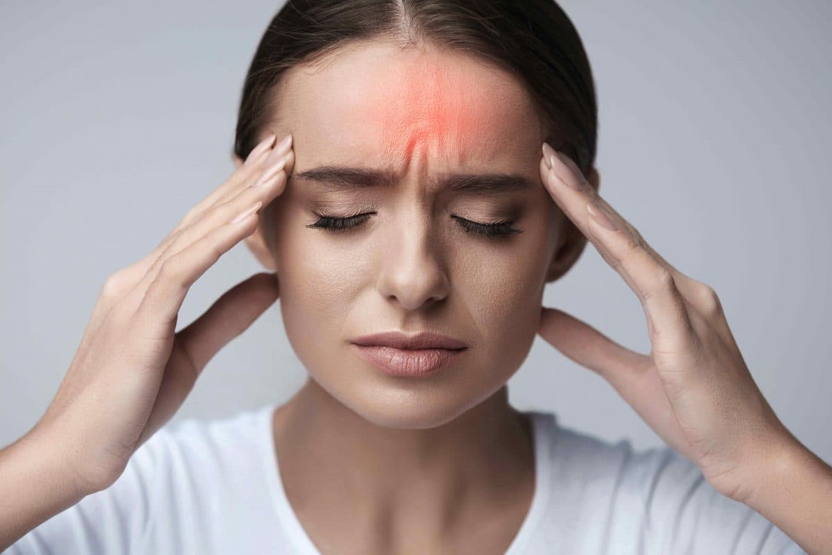 Middle-aged woman holding head with migraine pain - chiropractor San Antonio TX