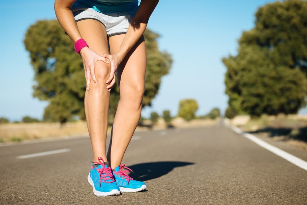 Runner holding knee with patellofemoral runner's knee pain - chiropractor San Antonio TX